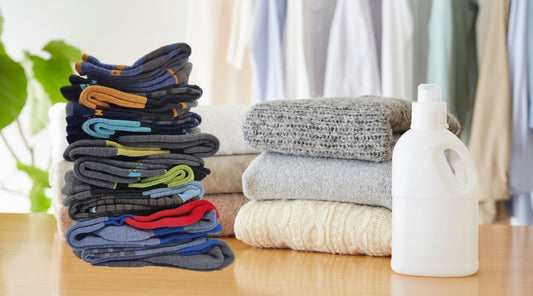 Neatly folded Laetts Merino and compression socks stacked beside wool sweaters and a bottle of gentle detergent on a wooden table — illustrating proper washing and care for premium performance socks