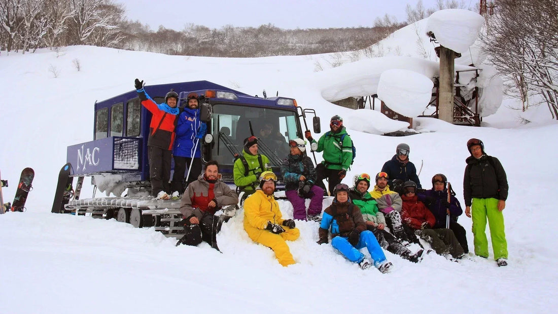 Group of skiers and snowboarders in bright winter gear gathered around a snowcat in deep snow—banner for Laetts HygroHeat™ highlighting FIR-powered warmth for cold mountain days.