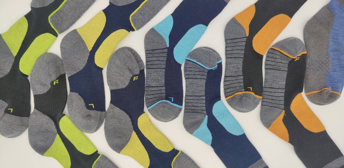 Array of Laetts BootGlide™ socks with various color patterns laid diagonally, highlighting low-friction heel/ankle panels—banner for BootGlide™ technology that makes ski and snowboard boots easier to slip on/off while staying secure in-boot.