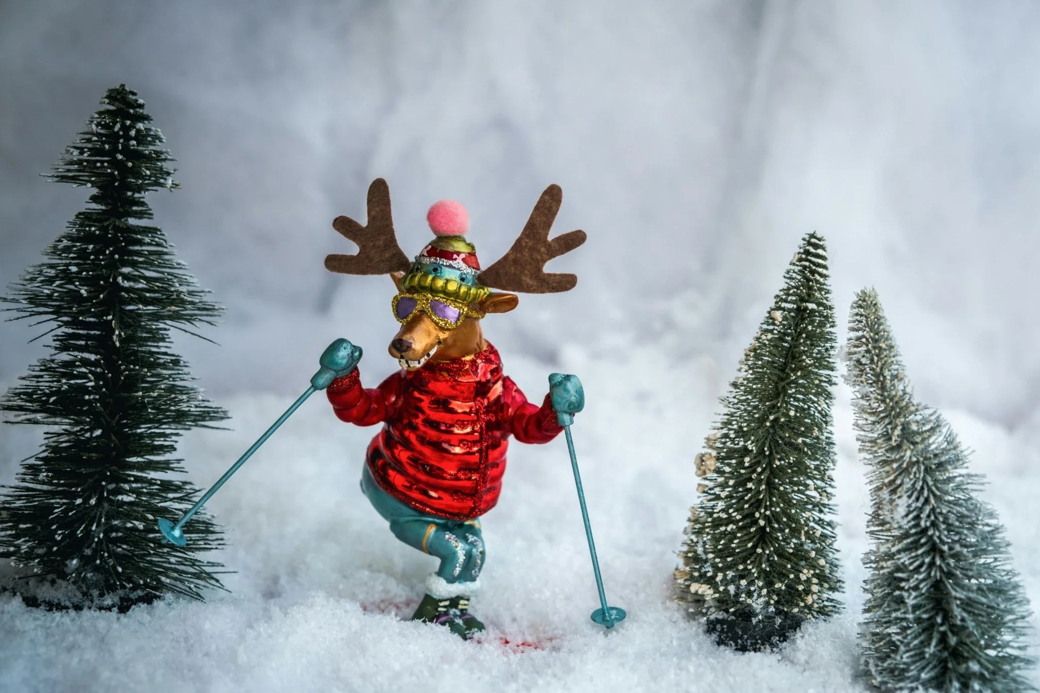 Holiday-themed banner image showing a whimsical reindeer skiing through snow, surrounded by snowy pine trees — festive winter gift collection.