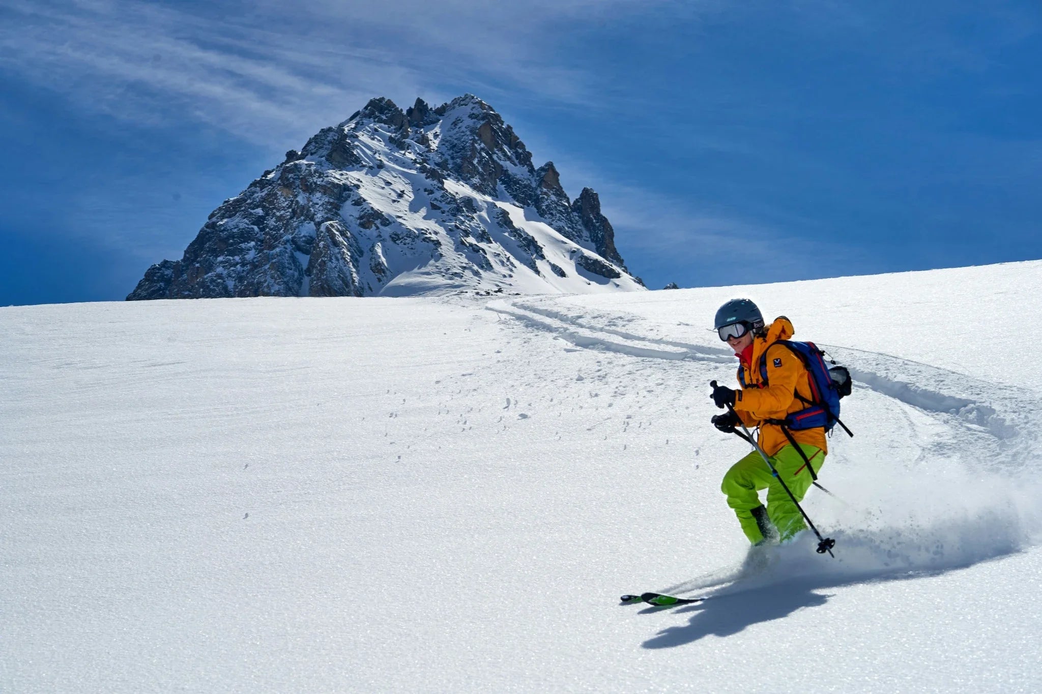 Skier carving down a snowy mountain at high speed under a clear blue sky, representing precision and performance — used to highlight Laetts Ultralight Ski Socks.