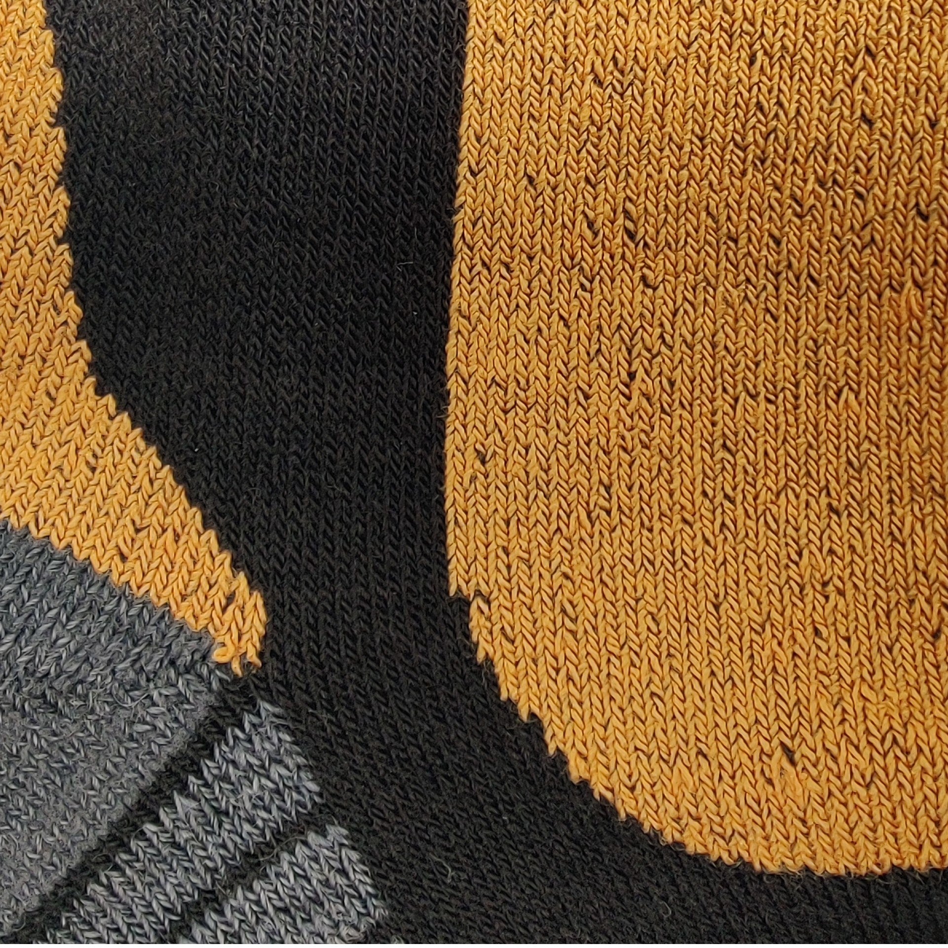 Close-up detail of Laetts ultralight men’s ski sock, showing the orange BootGlide™ low-friction zone, contrasting with black and gray knit sections. The texture highlights the Merino wool blend and patented HygroHeat™ thermal knitting.